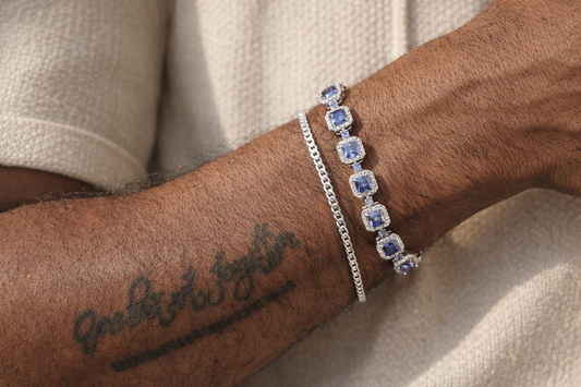 Close-up of a person's arm wearing two bracelets on a neutral background